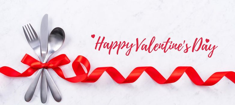 Valentine's Day holiday dating meal, banquet greeting card design concept - White plate and red ribbon on marble background, top view, flat lay.