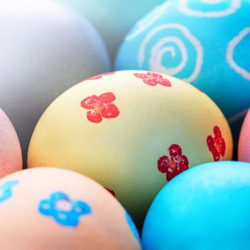 Colorful Easter eggs dyed by colored water with beautiful pattern on a pale blue background, design concept of holiday activity, top view, full frame.