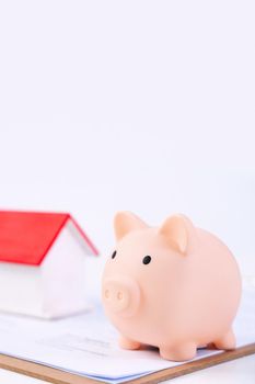 Financial concpet - Piggy bank, beautiful red white wooden house model on white background, saving money to buy insurance, close up, copy space.