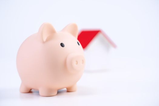 Financial concpet - Piggy bank, beautiful red white wooden house model on white background, saving money to buy insurance, close up, copy space.