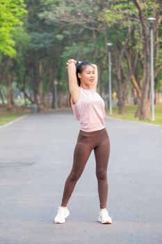 Wide shot and portrait of Asian sport woman do arm and back stretching on road of park during exercise in the morning.