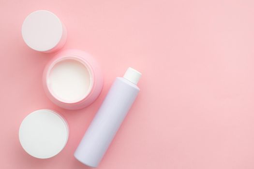 Layout on a pink cream background . Cosmetology. Care cosmetics. Skin care. Jars of cream. Pink background. Copy space. Article about the choice of cream. Spa. Spa treatments .