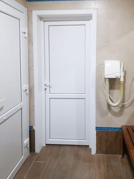 The interior of the shower room of the pool or spa center with a hairdryer and a door close-up