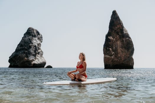 Close up shot of beautiful young caucasian woman with black hair and freckles looking at camera and smiling. Cute woman portrait in a pink bikini posing on a volcanic rock high above the sea