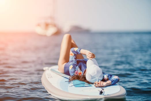 Woman sup yoga. Middle age sporty woman practising yoga pilates on paddle sup surfboard. Female stretching doing workout on sea water. Modern individual hipster outdoor summer sport activity