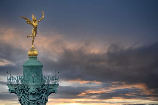 Close up detail of gilded winged Mercury atop the Bastille Column in Paris France with copy space on sunset sky background. Concept victory, liberty
