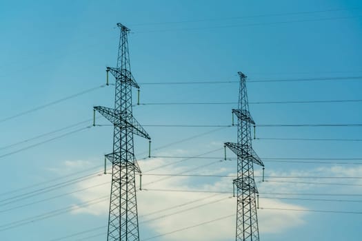 High voltage towers with sky background. Power line support with wires for electricity transmission. High voltage grid tower with wire cable at distribution station. Energy industry, energy saving.