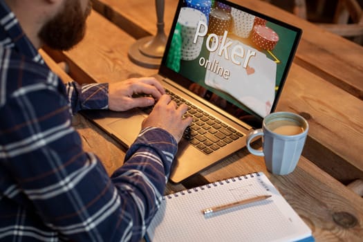 Game online concept. Close-up top view of a man playing poker on laptop. Young man playing via netbook during work-break in coffee shop, male sitting in front open laptop computer. Advertising content