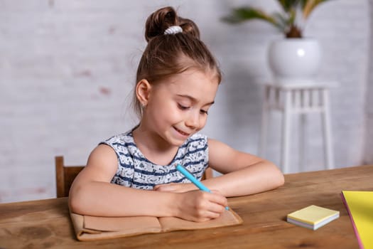 Inspired little girl at the table draw with crayons or do home work. Studying in elementary school. Home education