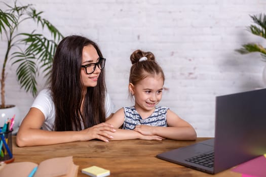 A young mother with little daughter are shopping on the Internet at personal computer. Online Family Shopping Concept