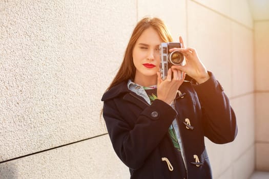 Portrait of a pretty young tourist taking photographs with vintage retro camera. Street style. Life style