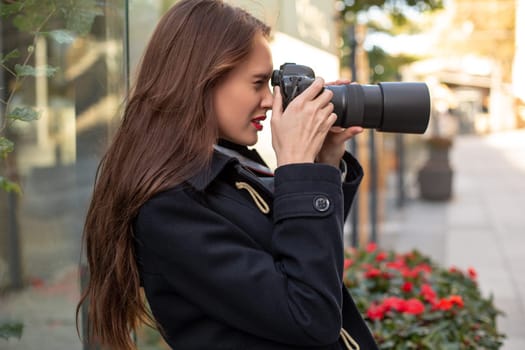 Happy woman on vacation photographing with camera on the city street. Having fun in the city with camera, travel photo of photographer.