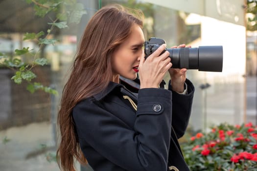 Portrait of professional female photographer on the street photographing on a camera. Photo shoot photosession in the city