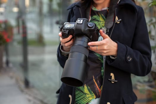 Close-up of professional female photographer on the street photographing on a camera. Photo shoot photosession in the city