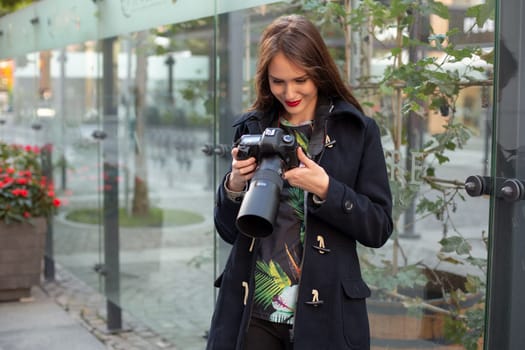 Portrait of professional female photographer on the street photographing on a camera. Photo shoot photosession in the city