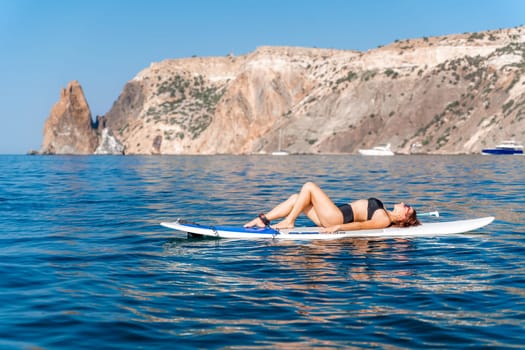 Sporty girl on a glanders surfboard in the sea on a sunny summer day. Summer activities by the sea.