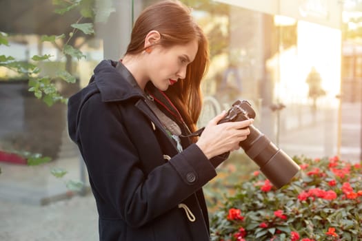 Portrait of professional female photographer on the street photographing on a camera. Photo shoot photosession in the city