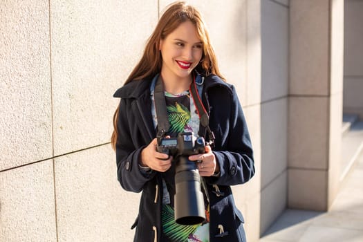 Happy woman on vacation photographing with camera on the city street. Having fun in the city with camera, travel photo of photographer.