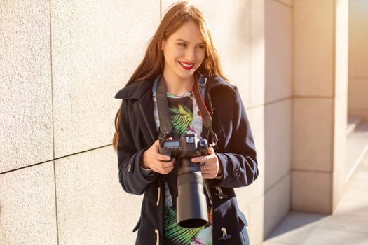 Happy woman on vacation photographing with camera on the city street. Having fun in the city with camera, travel photo of photographer.