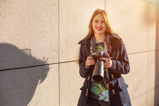 Happy woman on vacation photographing with camera on the city street. Having fun in the city with camera, travel photo of photographer.