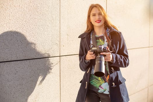 Happy woman on vacation photographing with camera on the city street. Having fun in the city with camera, travel photo of photographer.