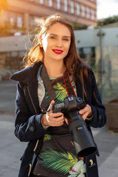 Portrait of professional female photographer on the street photographing on a camera. Photo shoot photosession in the city