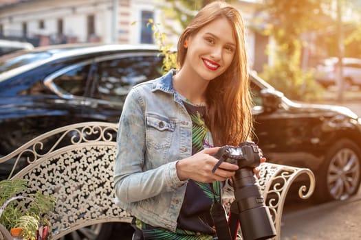 Portrait of professional female photographer on the street photographing on a camera. Photo shoot photosession in the city