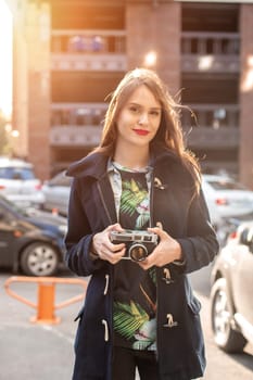 Portrait of a pretty young tourist taking photographs with vintage retro camera. Street style. Life style