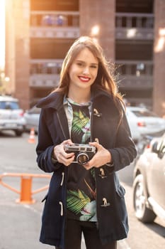 Portrait of a pretty young tourist taking photographs with vintage retro camera. Street style. Life style