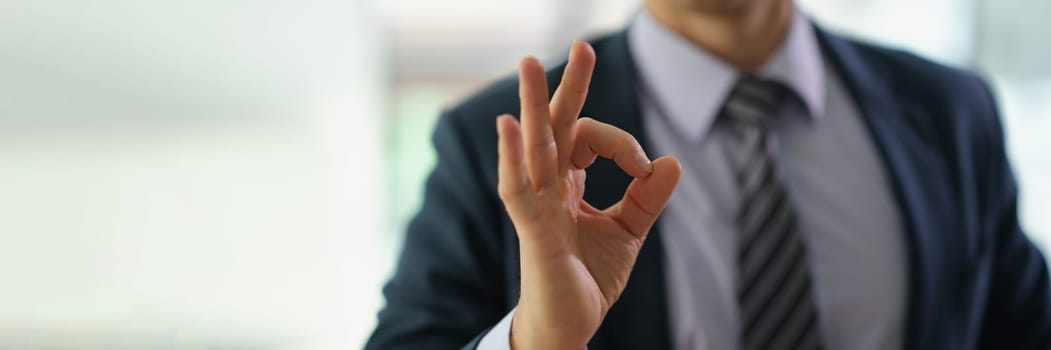 Businessman in suit showing hand gesture ok at work in office closeup. Approve good choice concept
