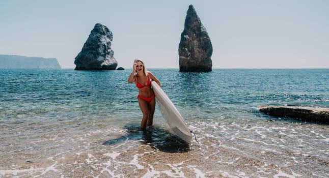 Close up shot of beautiful young caucasian woman with black hair and freckles looking at camera and smiling. Cute woman portrait in a pink bikini posing on a volcanic rock high above the sea