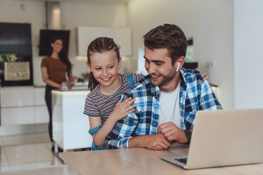 Father and daughter in the modern house talking together on a laptop with their family during holidays. The life of a modern family.