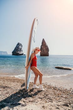 Close up shot of beautiful young caucasian woman with black hair and freckles looking at camera and smiling. Cute woman portrait in a pink bikini posing on a volcanic rock high above the sea