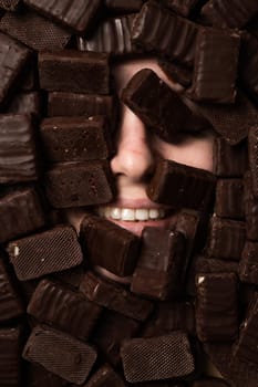 The face of a caucasian woman surrounded by sweets. Girl under a bunch of chocolates