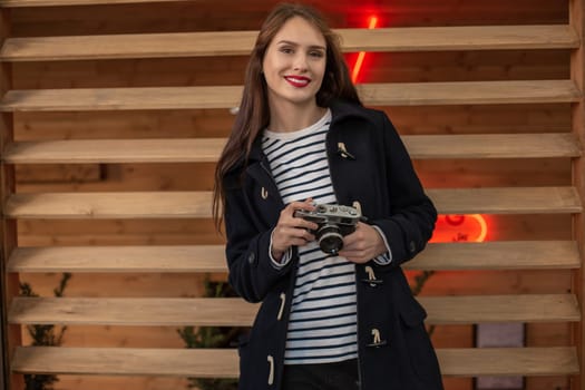 Happy young hipster woman holds retro photo camera. Having fun in the city with camera, travel photo of photographer.