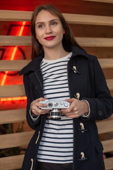 Happy young hipster woman holds retro photo camera. Having fun in the city with camera, travel photo of photographer.