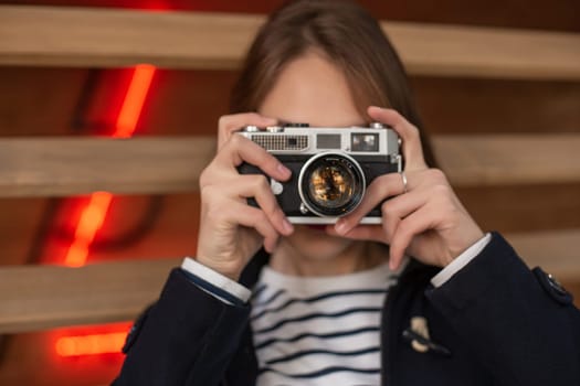 Happy young hipster woman holds retro photo camera. Having fun in the city with camera, travel photo of photographer.