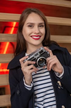 Happy young hipster woman holds retro photo camera. Having fun in the city with camera, travel photo of photographer.