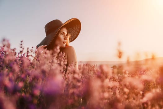 Close up portrait of young beautiful woman in a white dress and a hat is walking in the lavender field and smelling lavender bouquet.