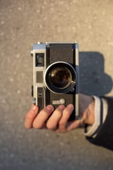 Girl photographer with an old camera in his hands. Stylish fashionable girl photographer in the city street