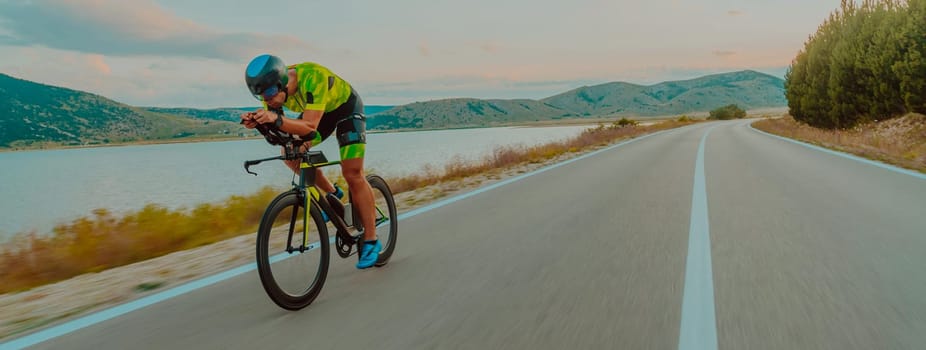 Full length portrait of an active triathlete in sportswear and with a protective helmet riding a bicycle. Selective focus.