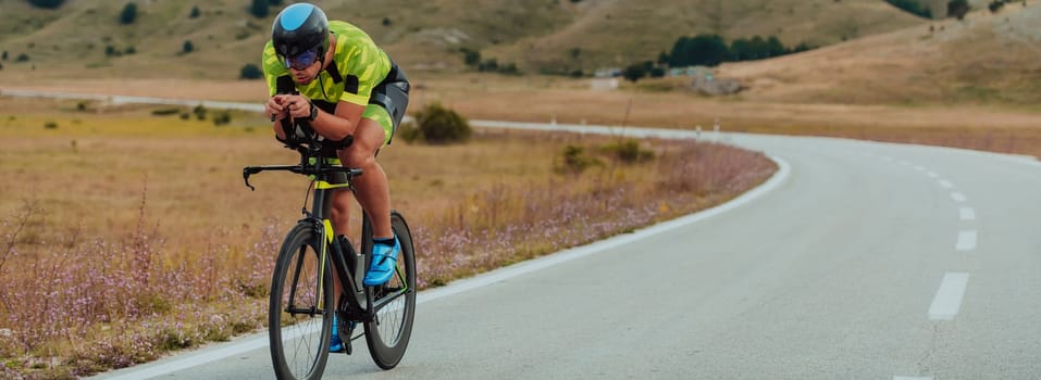 Full length portrait of an active triathlete in sportswear and with a protective helmet riding a bicycle. Selective focus.