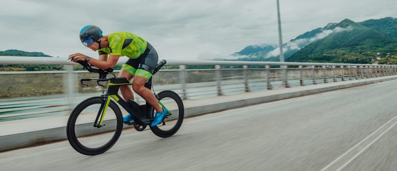 Full length portrait of an active triathlete in sportswear and with a protective helmet riding a bicycle. Selective focus .