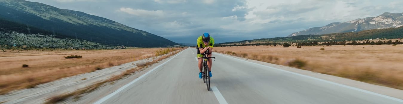 Full length portrait of an active triathlete in sportswear and with a protective helmet riding a bicycle. Selective focus.