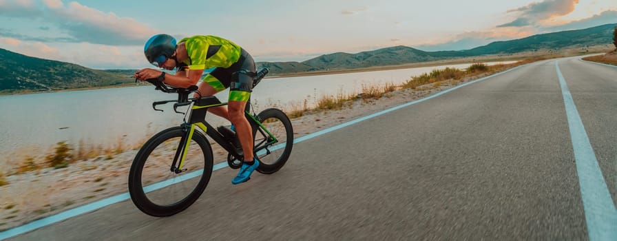 Full length portrait of an active triathlete in sportswear and with a protective helmet riding a bicycle. Selective focus.