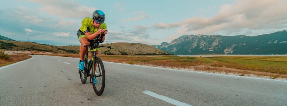 Full length portrait of an active triathlete in sportswear and with a protective helmet riding a bicycle. Selective focus.