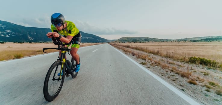 Full length portrait of an active triathlete in sportswear and with a protective helmet riding a bicycle. Selective focus.