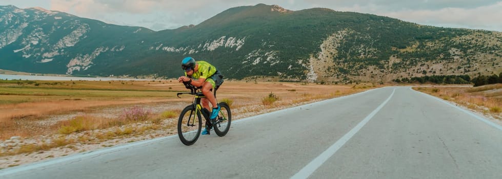 Full length portrait of an active triathlete in sportswear and with a protective helmet riding a bicycle. Selective focus.