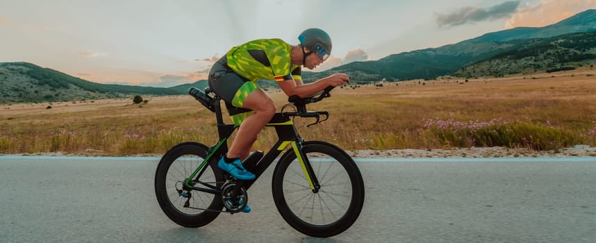 Full length portrait of an active triathlete in sportswear and with a protective helmet riding a bicycle. Selective focus.