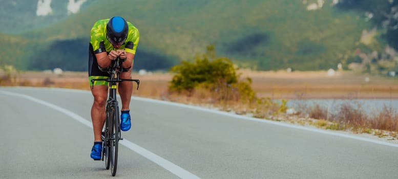 Full length portrait of an active triathlete in sportswear and with a protective helmet riding a bicycle. Selective focus.